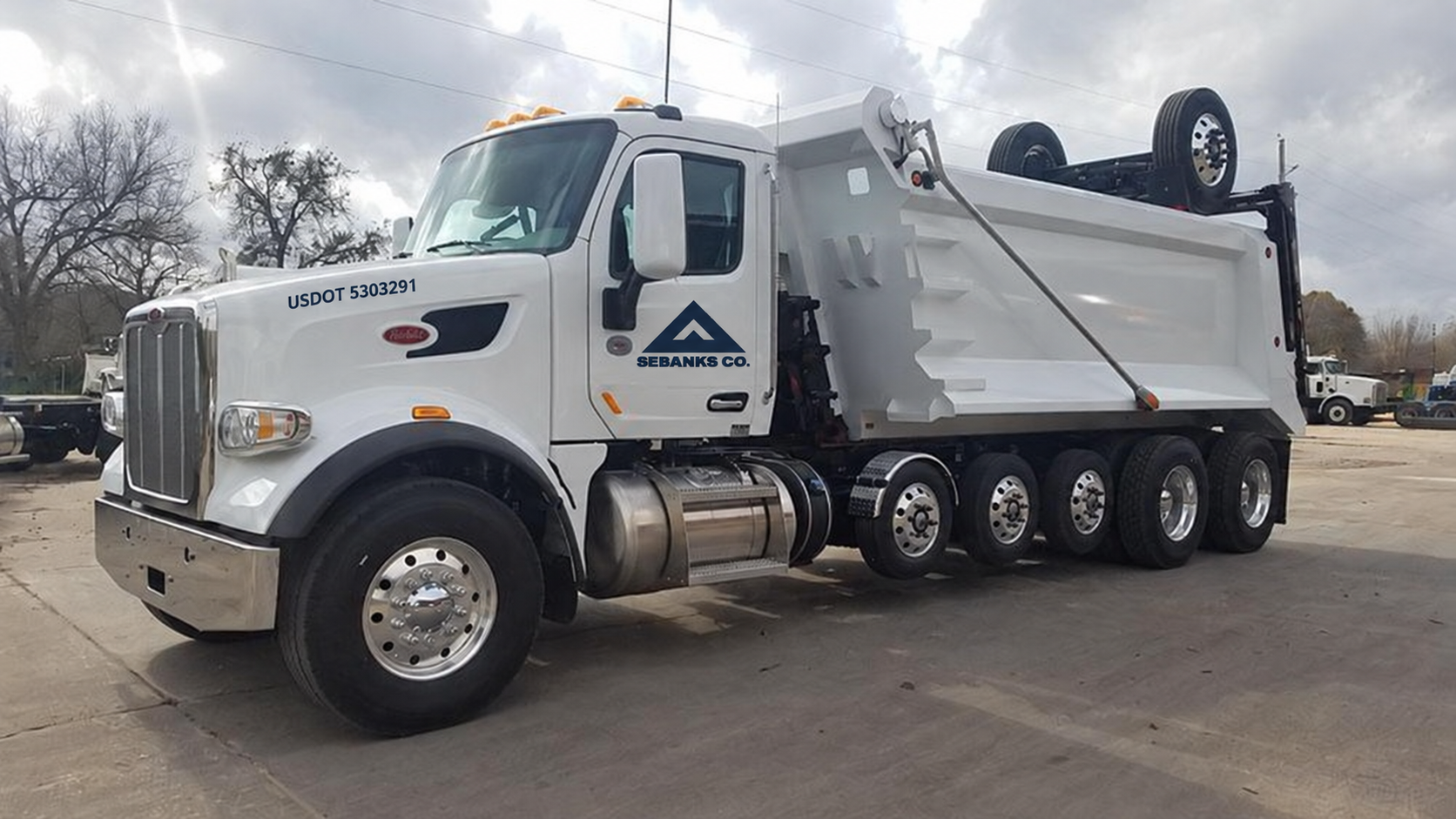 White Peterbilt super dump truck with Sebanks Co. logo on the door and USDOT 5303291 on the hood.